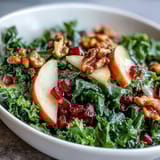 Colorful Kale and Pomegranate Bowl drizzled with apple cider vinaigrette and served fresh in a white ceramic bowl.  