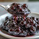 Glazed Black Currant Jelly shines in a clear glass jar, perfect for filling pastries or topping yogurt and desserts.