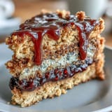 A cross-section of PB and J Cake With Black Currant Sauce reveals creamy peanut butter crumb and a vibrant, tangy black currant jam center.