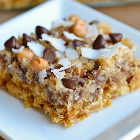 Chewy, delicious Magic Cookie Bars displayed with a buttery graham cracker crust and toppings.