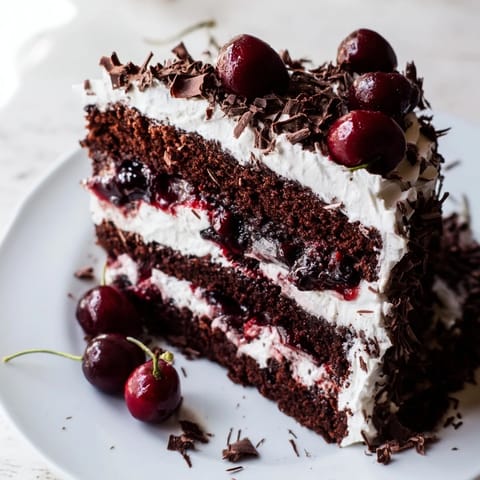 Luscious Black Forest Cake with dark chocolate shavings, fresh cherries, and a generous whipped cream frosting.