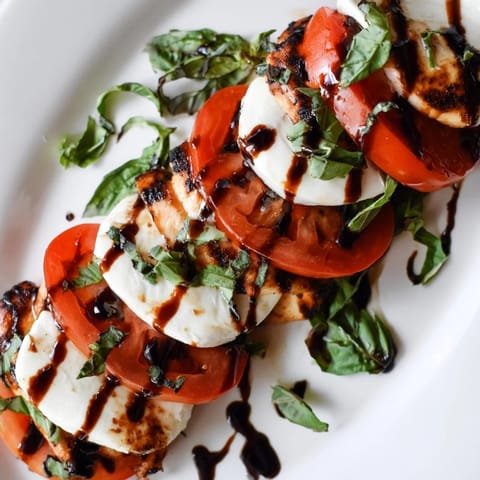A vibrant Chicken Caprese Salad featuring juicy grilled chicken, ripe tomatoes, creamy mozzarella, and a balsamic drizzle.  