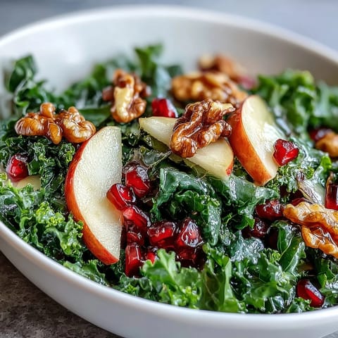 Colorful Kale and Pomegranate Bowl drizzled with apple cider vinaigrette and served fresh in a white ceramic bowl.  