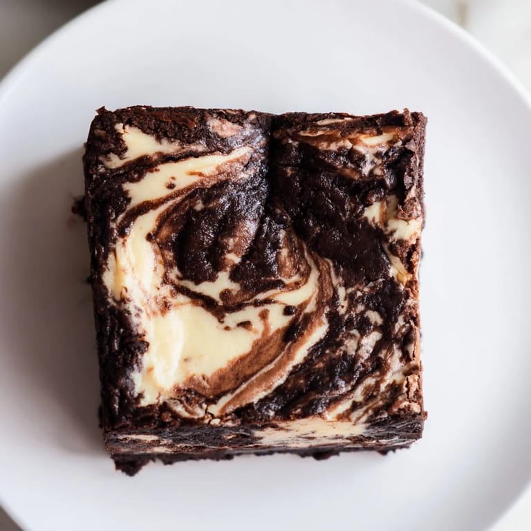 Freshly baked cheesecake brownies, beautifully swirled, promise a fudgy brownie with creamy cheesecake textures.