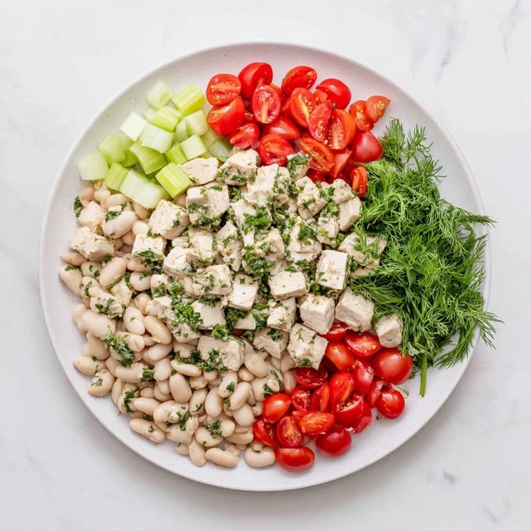Hearty Lemony White Bean Chicken Salad served in a white bowl, featuring juicy tomatoes and red onion, perfect for a light lunch or summery main dish.