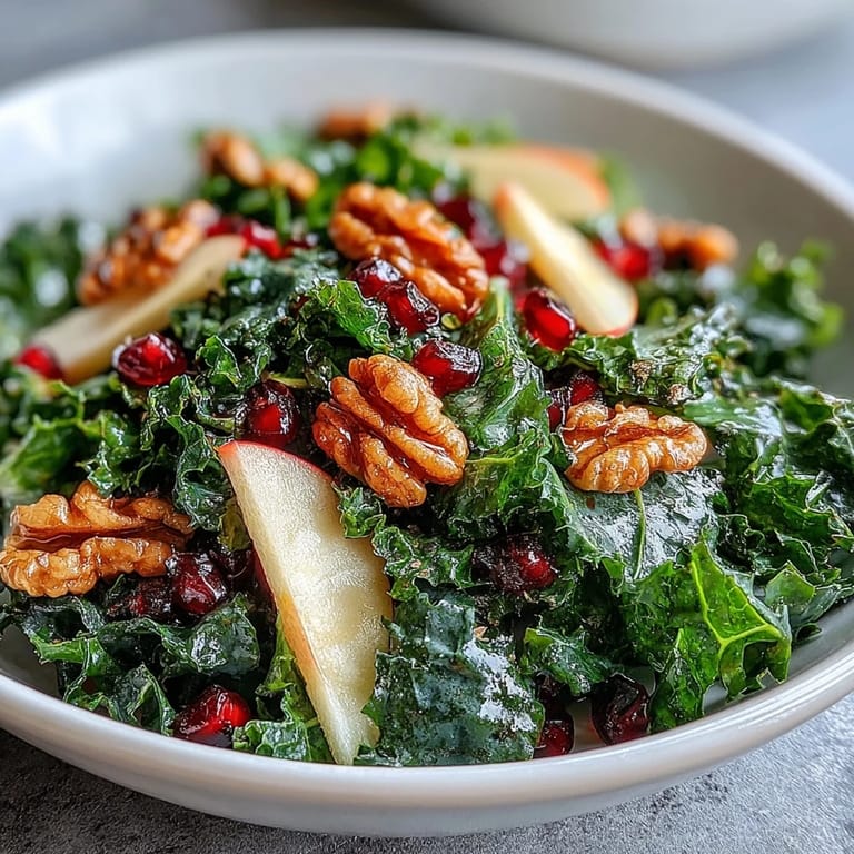 Healthy vegetarian salad featuring tender kale, sweet pomegranate arils, and toasted walnuts for a satisfying crunch.