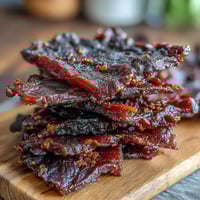 Black Currant Smoky Jerky strips with a deep mahogany color and a glossy, sticky glaze.